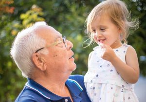 Grandparent holds child up high while in the garden