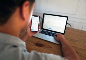 Person sits in front of a laptop, while holding phone, sending a wire transfer